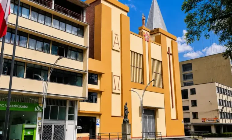 Torre de iglesia de color ocre con una gran cruz en el centro urbano de Calarcá