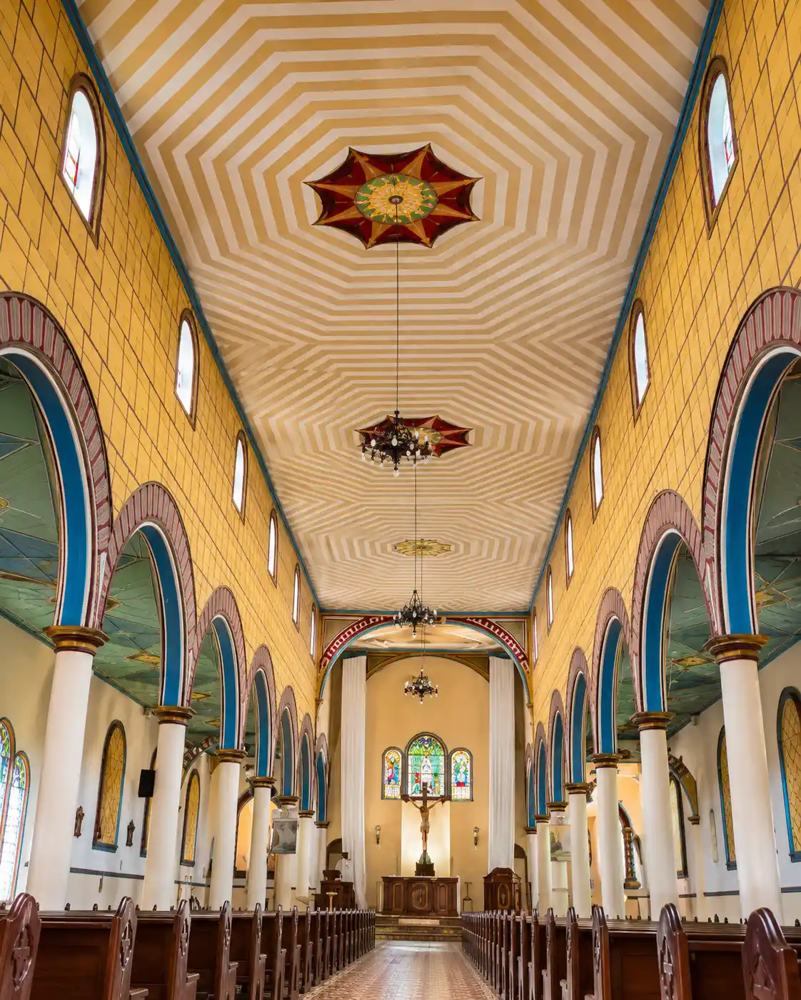 Nave interior de la Iglesia Inmaculada Concepción de Filandia con arcos de colores y vitrales