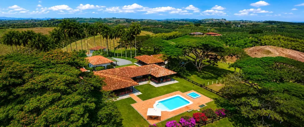 Vista aérea de una finca con piscina rodeada por el paisaje cafetero del Quindío