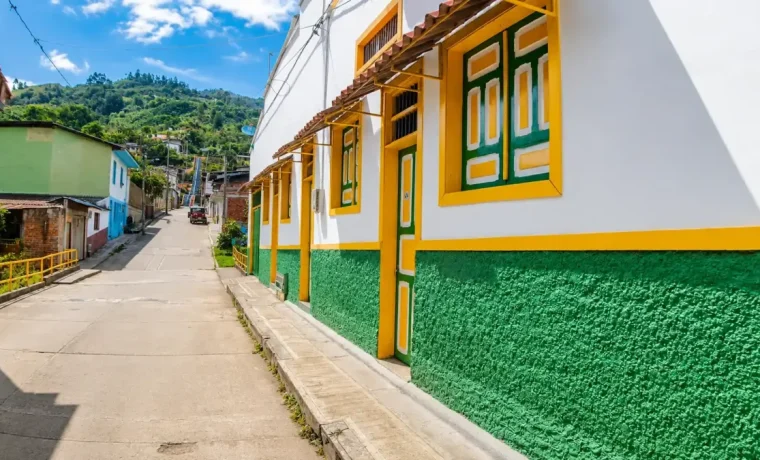 Calle inclinada de Pijao con fachadas blancas, verdes y amarillas de arquitectura tradicional