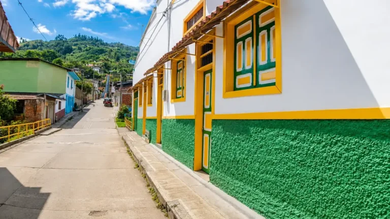 Calle inclinada de Pijao con fachadas blancas, verdes y amarillas de arquitectura tradicional