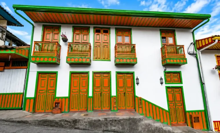 Casa tradicional de fachada blanca con puertas, ventanas y balcon verde en Salento, Quindío