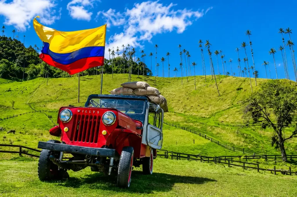 Jeep Willys rojo con bandera de Colombia frente a las palmas de cera del Valle de Cocora