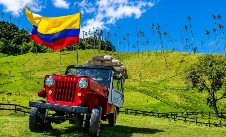 Jeep Willys rojo con bandera de Colombia frente a las palmas de cera del Valle de Cocora